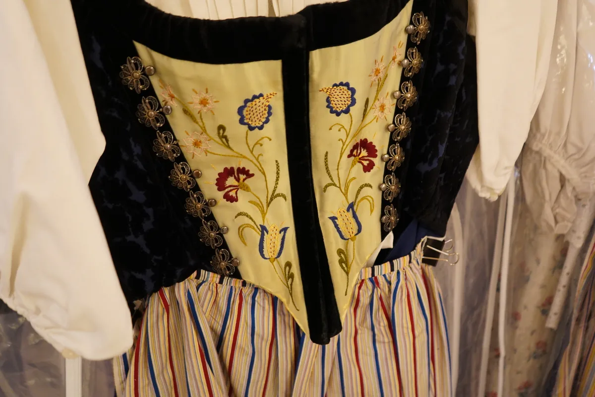 Ein Bustier einer Appenzellertracht, gelb, mit gestickten Blumenverzierungen und goldenen Blumenbroschen.